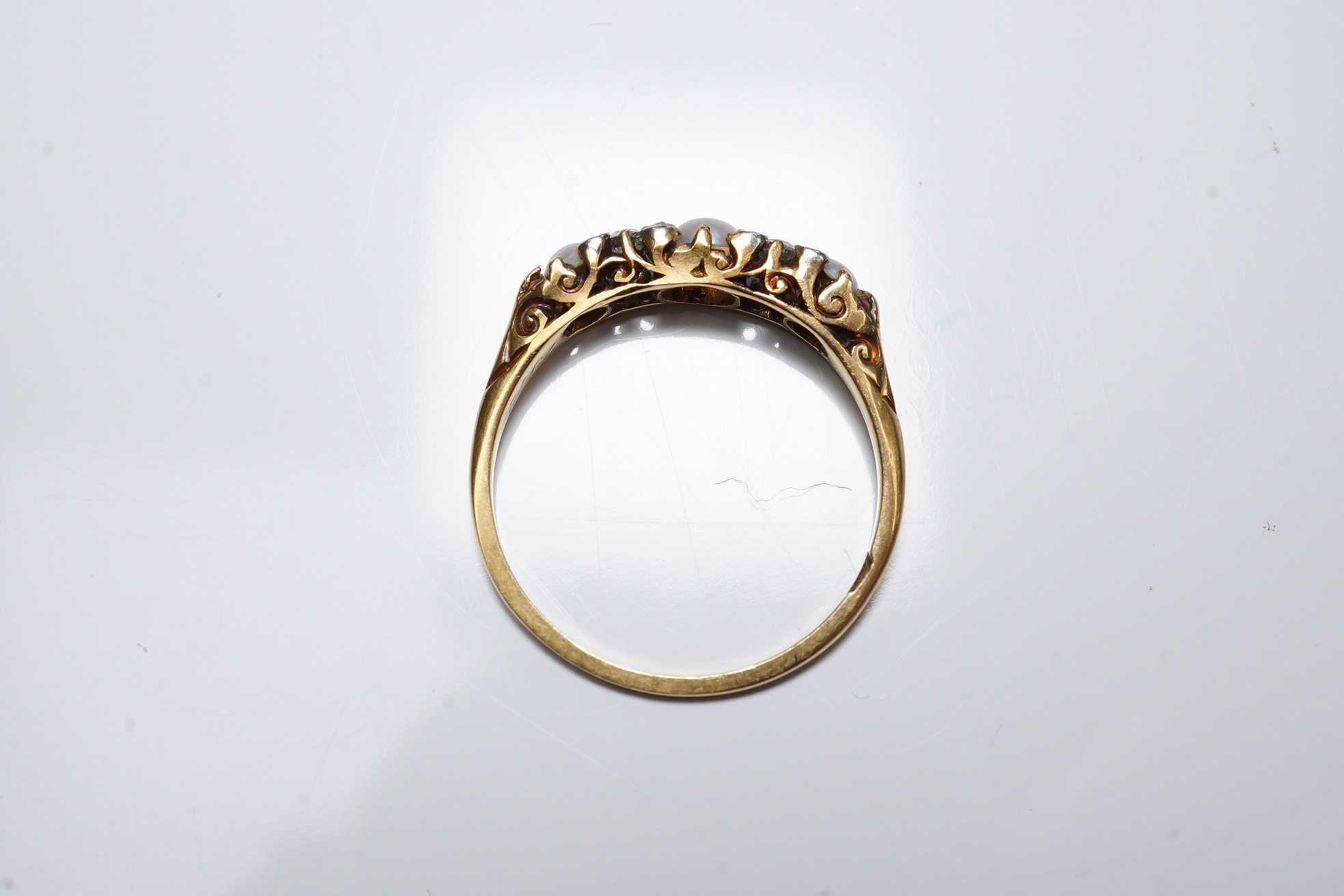 An early 20th century yellow metal (stamped 18), two stone diamond and three stone split pearl set half hoop ring, size O, gross weight 2.2 grams. Condition - fair